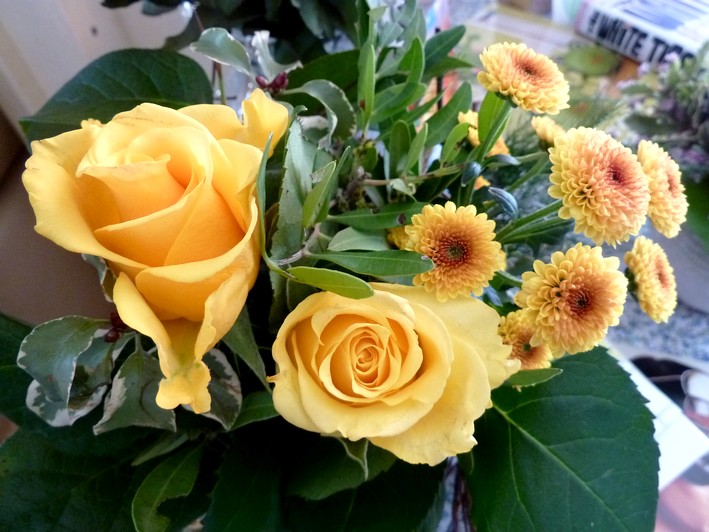 yellow roses and tiny yellow sunflower-like flowers tied up with birch branches